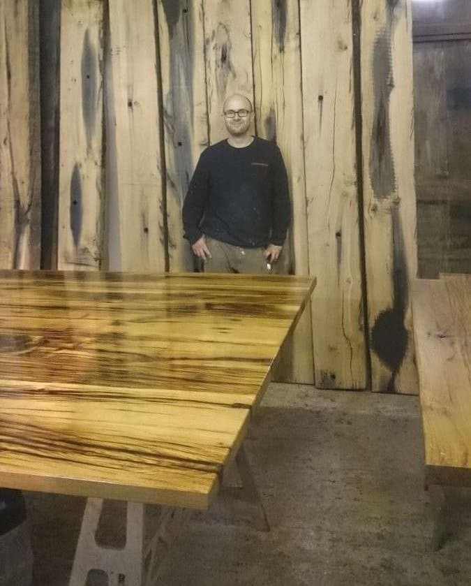 Milan Oesert in front of massive wood planks in the carpentry workshop